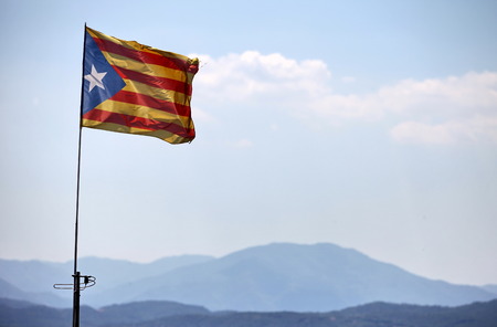 Catalan flag with pole blowing in the wind on blue sky with cloudの写真素材