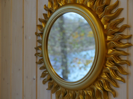 golden mirror in the shape of the sun on the wallの写真素材