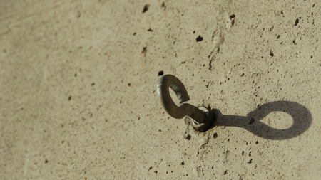 steel bolt anchor eye in the wall shadow