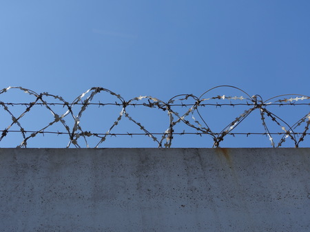 concrete wall with barbed wire razor wire low angle view