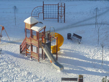playground in the morning in winter in the snow lit by the sun is waiting for children and parentsの写真素材