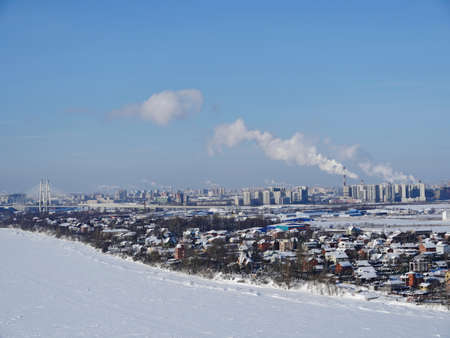 Bird's eye view of a suburban village on the banks of a river in winter, a river and small houses under the snow, a cozy calm suburban life in natureの写真素材