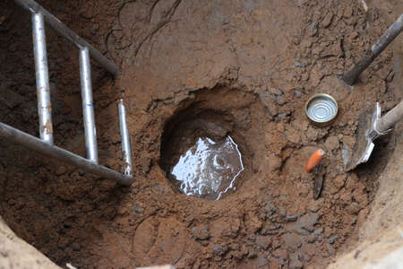 groundwater has appeared at the bottom of a deep round well with hand tools