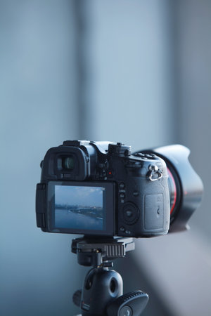 photo camera mounted on a tripod in progress video filming rear view close-up