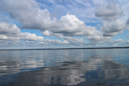 celestial landscape cumulus clouds reflected in blue sea waterの写真素材