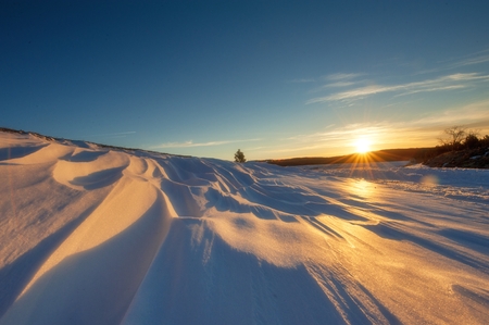 winter landscape snow-covered fields and roads in sunlight rays on the sunsetの写真素材