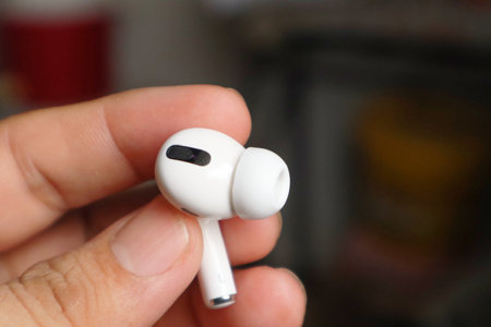 A close-up shot of white AirPods cradled in a hand, showcasing the epitome of style and convenience.の写真素材