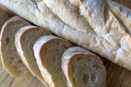 A freshly sliced baguette on a wooden chopping boardの写真素材
