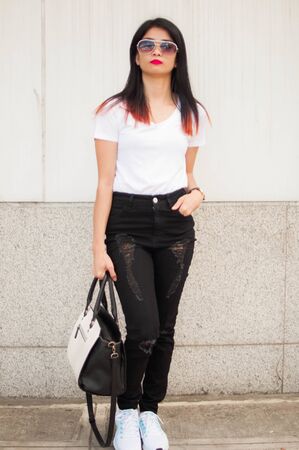 A portrait of a young woman with hand bag in the city sidewalkの写真素材