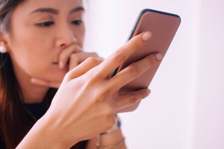 A depressed young woman is using a mobile phone