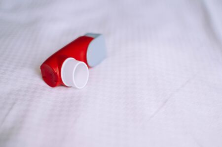 A still life of red and white asthma inhaler devise on a white backgroundの写真素材