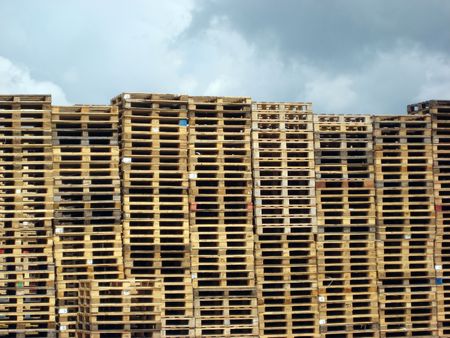 Stacks of wooden pallets against cloudy sky