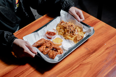 Hands of a man holding a plate of fried chicken with riceの写真素材