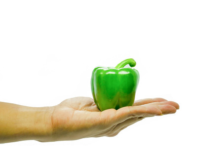 Hand is holding a green bell pepper.の写真素材