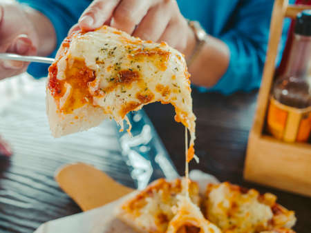 Delicious traditional pepperoni pizza With the hand that was scooping On the board on the white wooden table.の写真素材