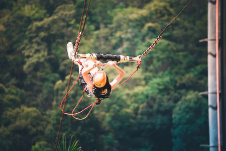 Activity sport of a woman floating in the air while playing a big swingt there is a natural forest background.の写真素材