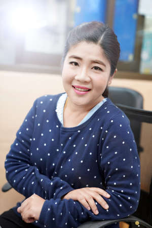 An Asian woman smiling in a chair Wear a black t-shirt Sit on a chair.の写真素材