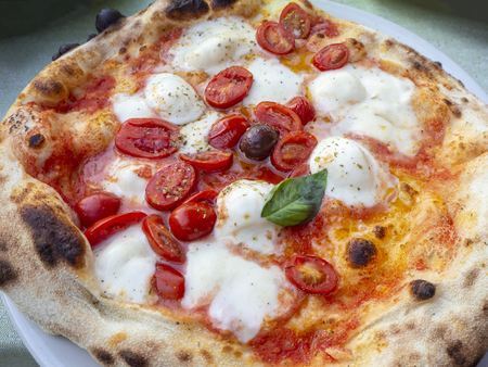 Delicious Italian pizza with cherry tomatoes, cooked in the wood ovenの写真素材