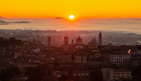 Bergamo, one of the most beautiful city in Italy. Amazing landscape at the old town during the sunrise. The fog covers the plain around the town. Fall season. Warm colors contestの写真素材