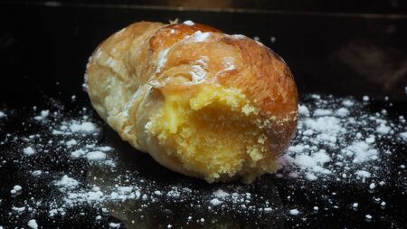 Close-up delicious cannoncino or puff pastry horn filled with custard.の写真素材