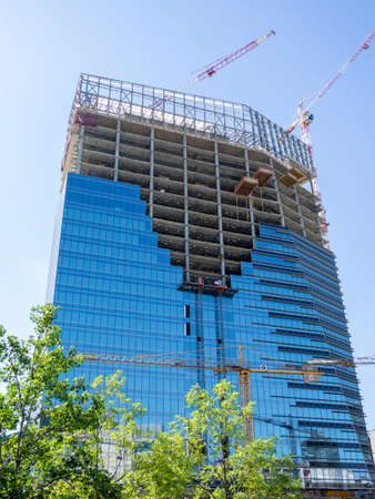 Milan, Italy. New skyscrapers under construction. Construction site with cranes, elevators and scaffolding. New building at the financial districtのeditorial素材