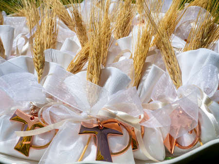 Gifts or favors for the first or holy communion. Small bags of white fabric with ear of wheat and Tau Christian cross. Religious symbolの写真素材