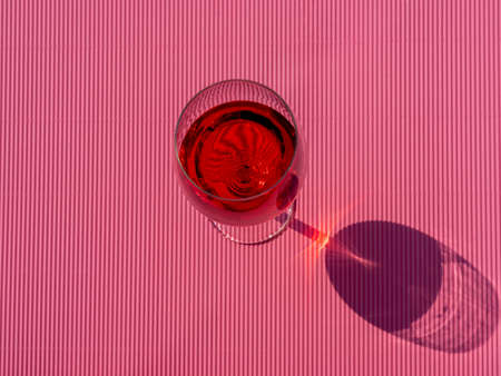 Alcoholic red aperitif in crystal glass. Glass isolated on pink background. Projection of the shadow of the glassの写真素材