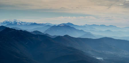 Amazing drone aerial landscape at the Italian Alps in winter and autumn. Morning panorama. Fall sunrise at the alps with moisture and pollution in the air. Silhouette of the mountains and hillsの写真素材
