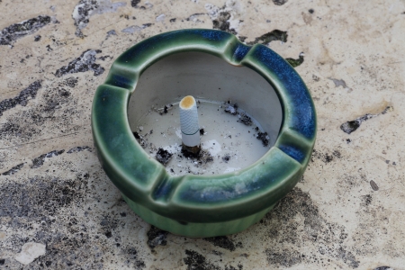 Ceramic ashtray with cigarette on the stone tableの写真素材