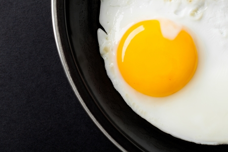 Fried Egg on Black Frying Pan, Close Up on Yolkの写真素材