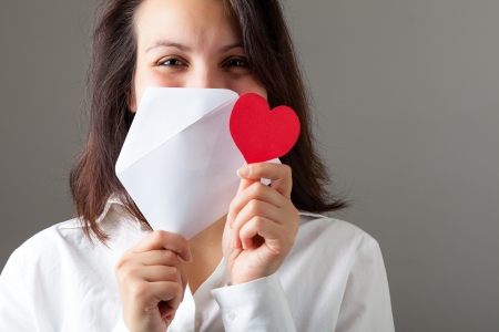Smiling Woman Holding a Red Heart and an Envelopの写真素材