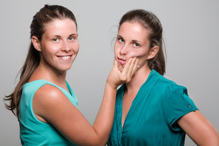 Woman Squeezing Her Twin Sister' Cheeks