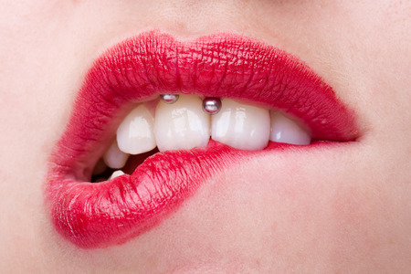 Woman with Smiley Piercing Biting Her Lips with Red Lipstickの写真素材