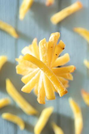 Stacked French Fries on Blue Wooden Surfaceの写真素材