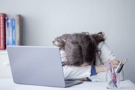 Tired Young Woman Doctor Working with a Laptop in a Clinic