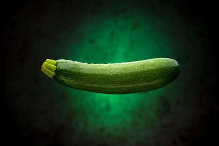Wet Courgette Floating with Green Backgroundの写真素材