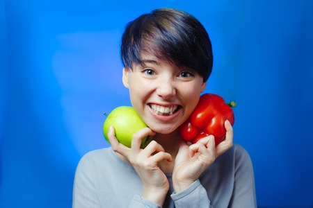 Portrait of young woman with apple and pepperの写真素材