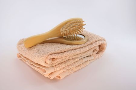 A wood hair brush and small mirror on an apricot colored towelの写真素材