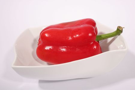 A bright fresh red bell pepper in a white bowl against a white backgroundの写真素材