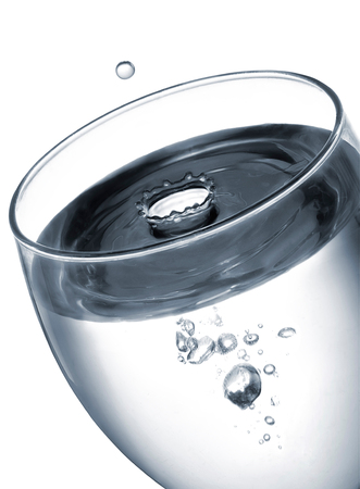 close up at a glass of water while a drop is falling into itの写真素材