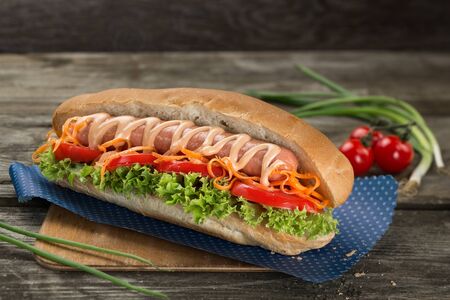 Appetizing hot dog with vegetables close up on a woodenの写真素材