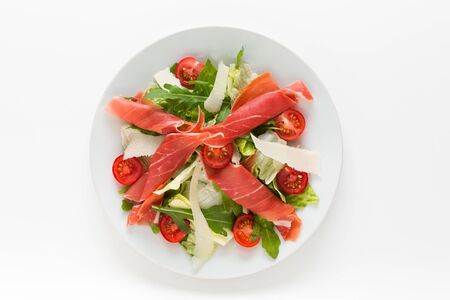 Fresh salad with prosciutto ham, parmesan and cherry tomatoes top view on a whiteの写真素材