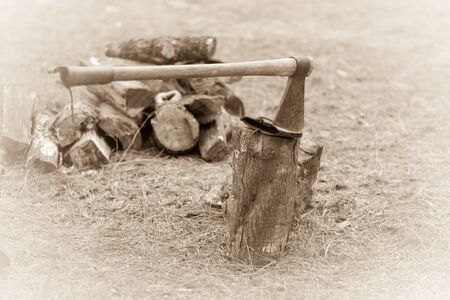 Hatchet buried in a piece of leather on a wood block.のeditorial素材