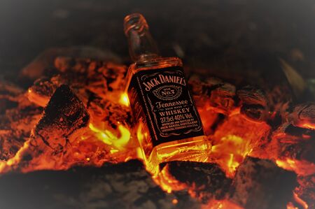 Saint Petersburg, Russia. 09 09 2017. Bottle of whiskey Jack Daniels on fire with burning charcoals in the nightのeditorial素材