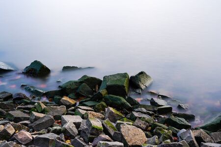 Colorful rocky beach near ideal misty calm water.の写真素材