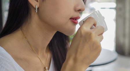 Closeup of Asian woman drinking coffee.の写真素材