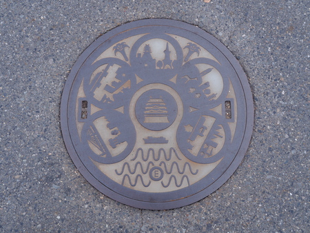 NAGOYA, JAPAN - NOVEMBER 16, 2015: A manhole cover in Nagoya, Japan. Signs and symbols of important places that represent Nagoya engraved on to a manhole along a street in Nagoya city.のeditorial素材