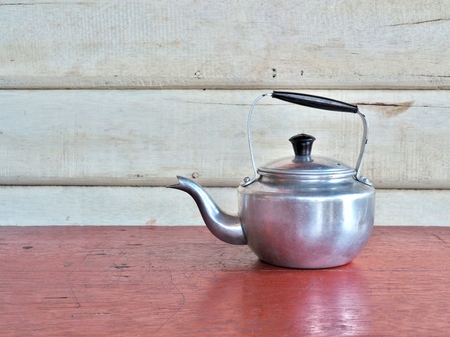 Antique Aluminum Kettle on wooden table, wooden wall as background. Vintage Concept.の写真素材