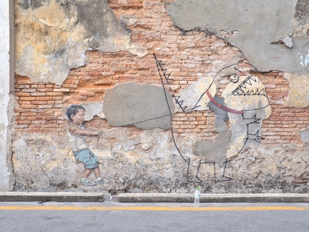 Penang, Malaysia - May 11, 2017: Little Boy with Pet Dinosaur, street art  painted by Ernest Zacharevic in Georgetown city, Penang, Malaysia.のeditorial素材