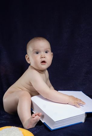 Child sits with book on turn blue backgroundの写真素材